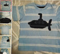 Blue striped shirt with black submarine design on a bed