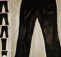 Black leather pants displayed against a striped background with a shelf on the left.