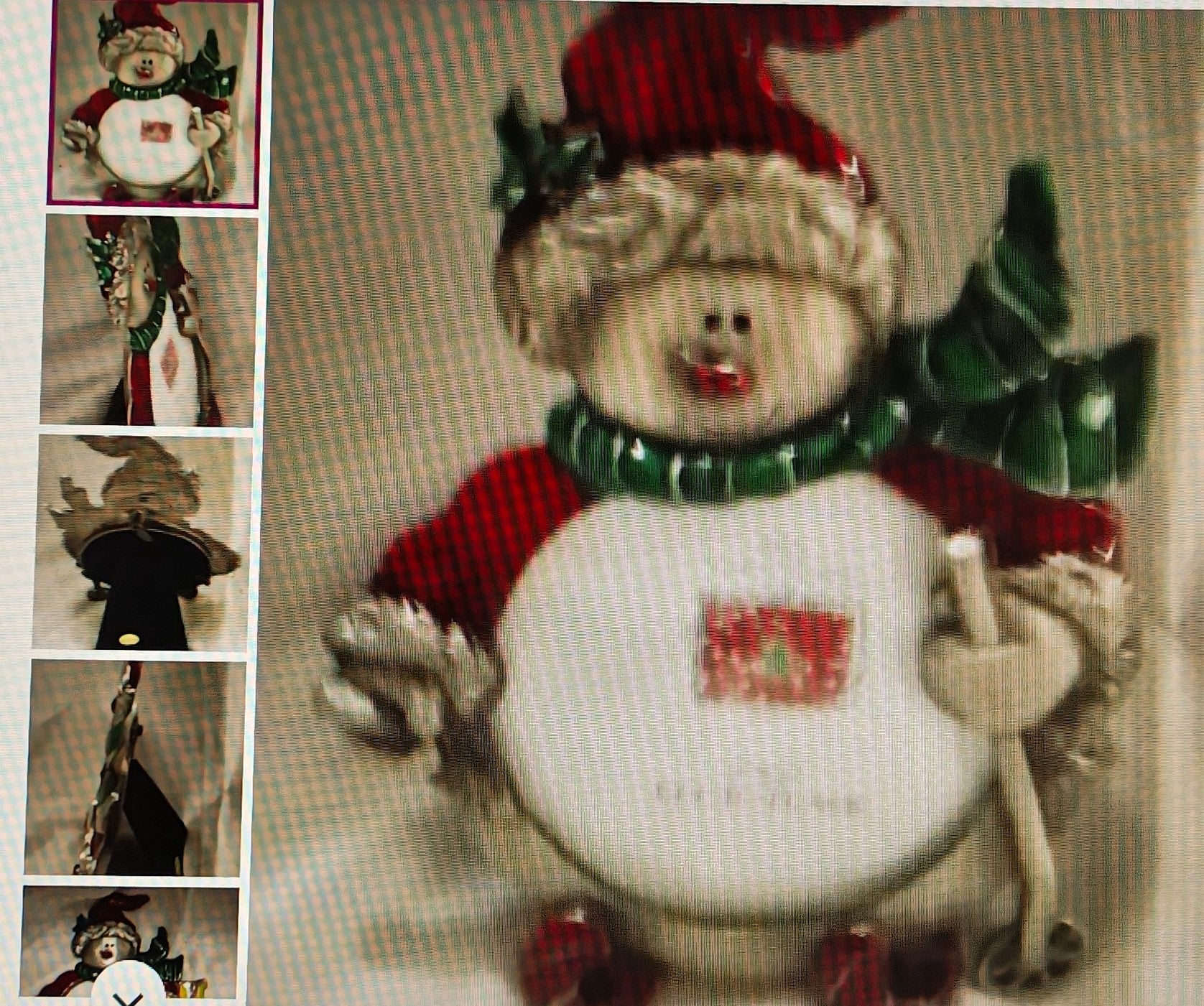 Decorative snowman ornament with a red hat and green scarf on a textured background.