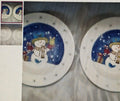 Two ceramic plates with snowman designs on a metallic surface.