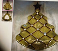 Decorative glass Christmas tree ornament with a star on top, shown on a reflective surface.
