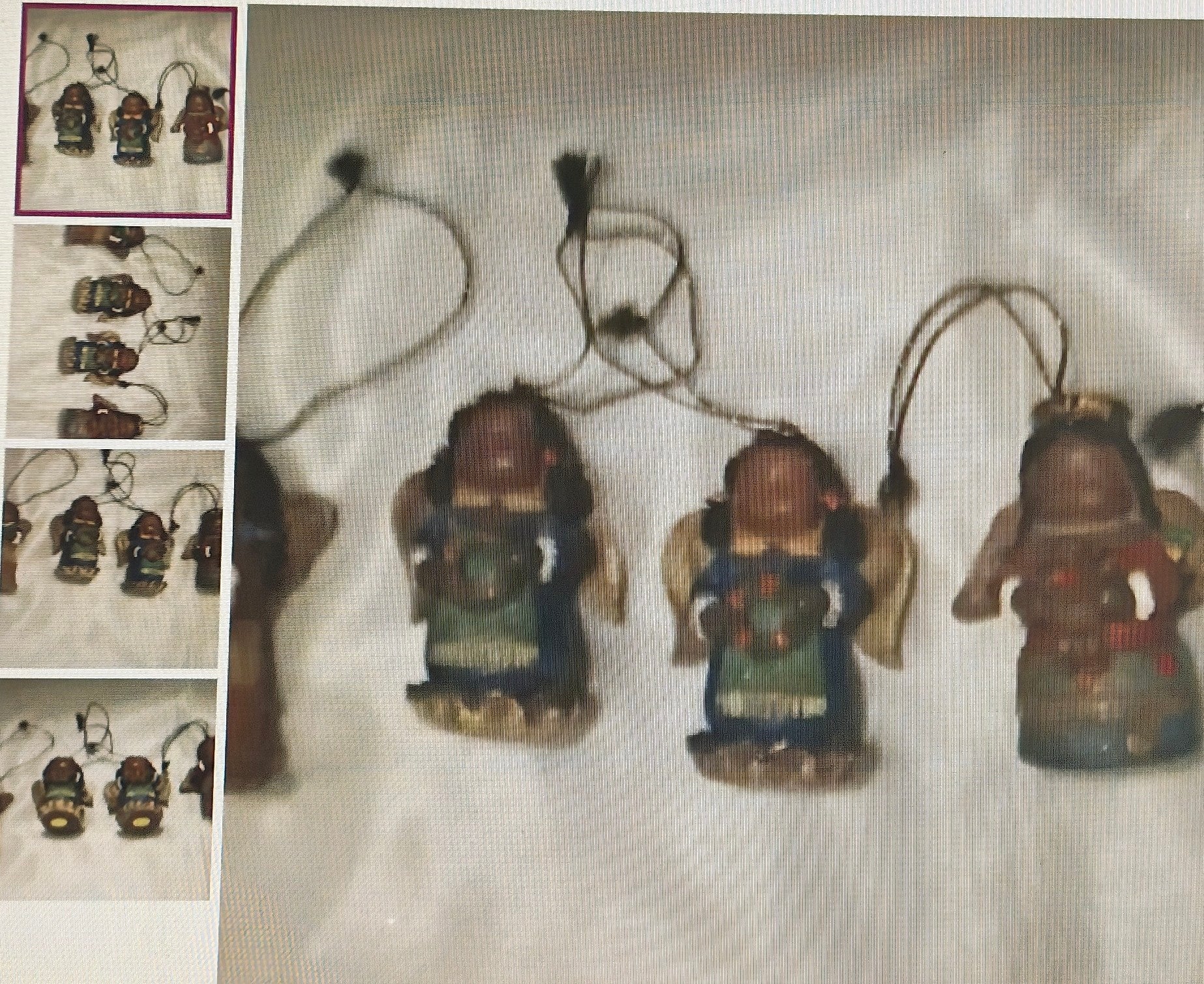 Three small figurines hanging from strings on a textured surface.