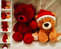 Two teddy bears, one red and one brown with a 'First Christmas' hat, on a textured surface.