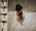 Small snowman figurine with a black top hat and plaid scarf on a textured surface.