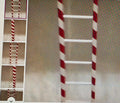 Red and white striped ladder on a textured surface