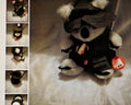 Plush toy panda in a black outfit with a red tag on a light background