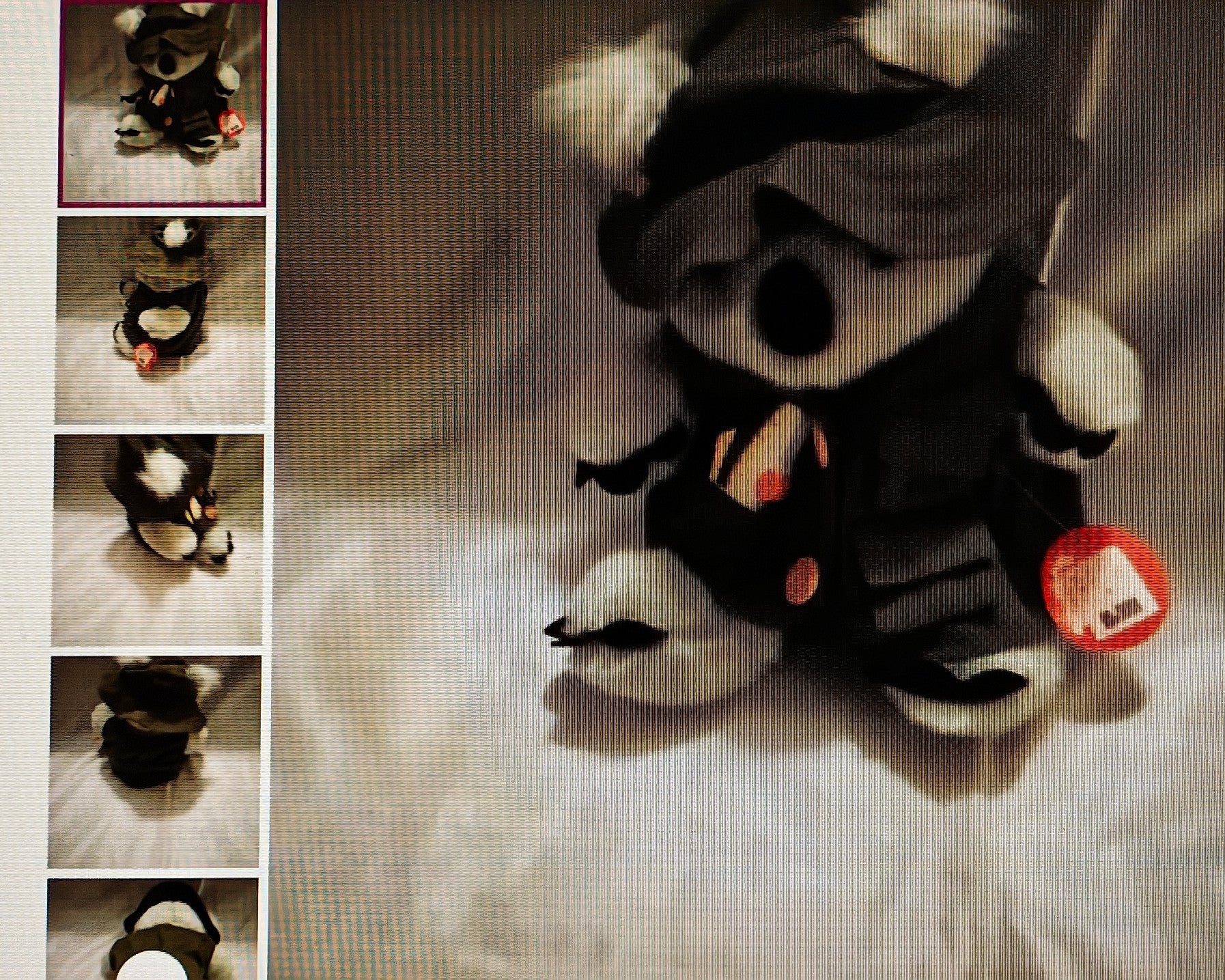 Plush toy panda in a black outfit with a red tag on a light background