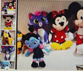 Collection of plush toys including cartoon characters on a textured surface.