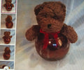 Brown teddy bear with a red scarf and blue heart on a textured light background
