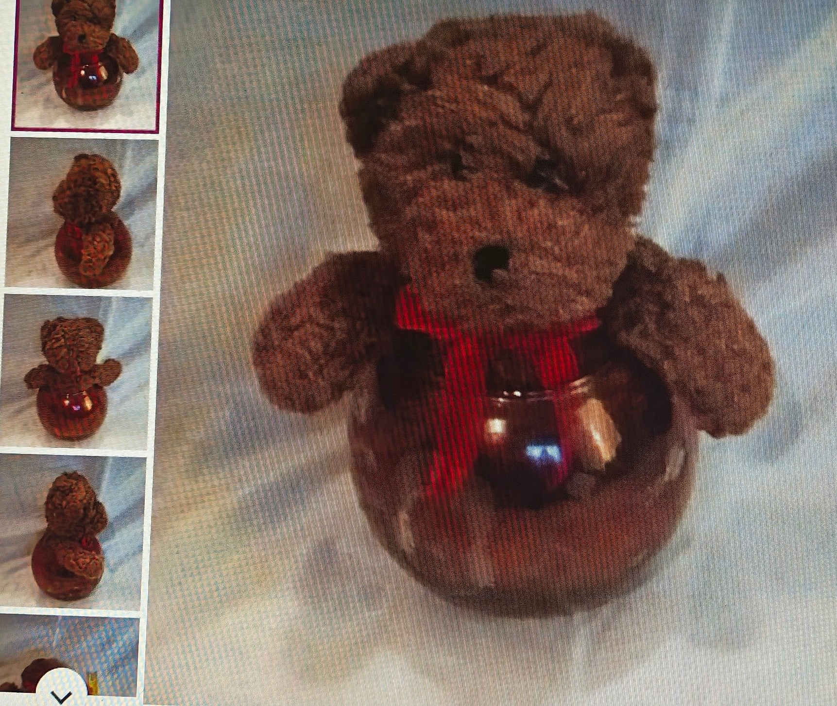 Brown teddy bear with a red scarf and blue heart on a textured light background