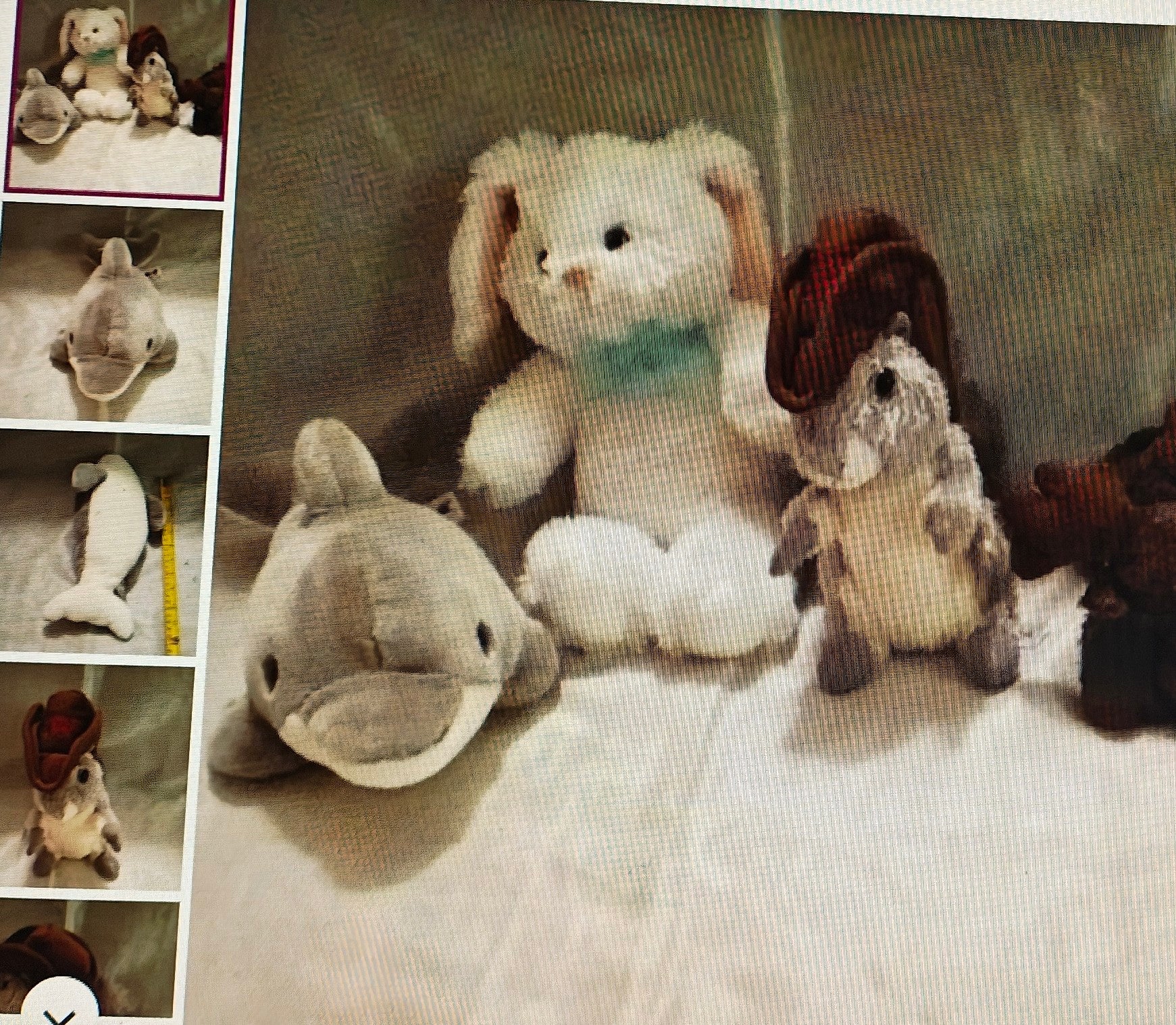 Collection of stuffed animals including a rabbit, dolphin, and others on a textured surface.