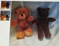 Two teddy bears, one brown and one black, on a white surface with a blue blanket in the background.