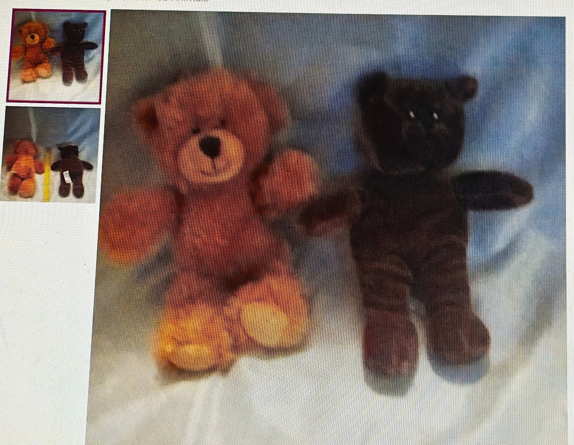 Two teddy bears, one brown and one black, on a white surface with a blue blanket in the background.