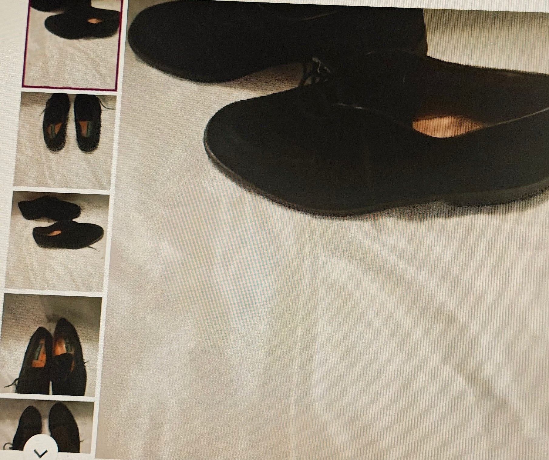 Black shoes on a textured surface with a small mirror reflection.