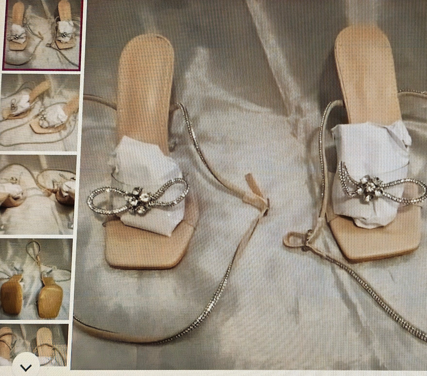 Beige sandals with decorative chain and bow on a textured surface