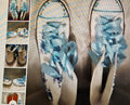 Pair of flip-flops with blue floral design on a metallic surface