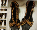 Pair of black shoes with leopard print straps on a textured surface.