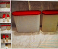 Two white storage containers with red lids on a textured surface.
