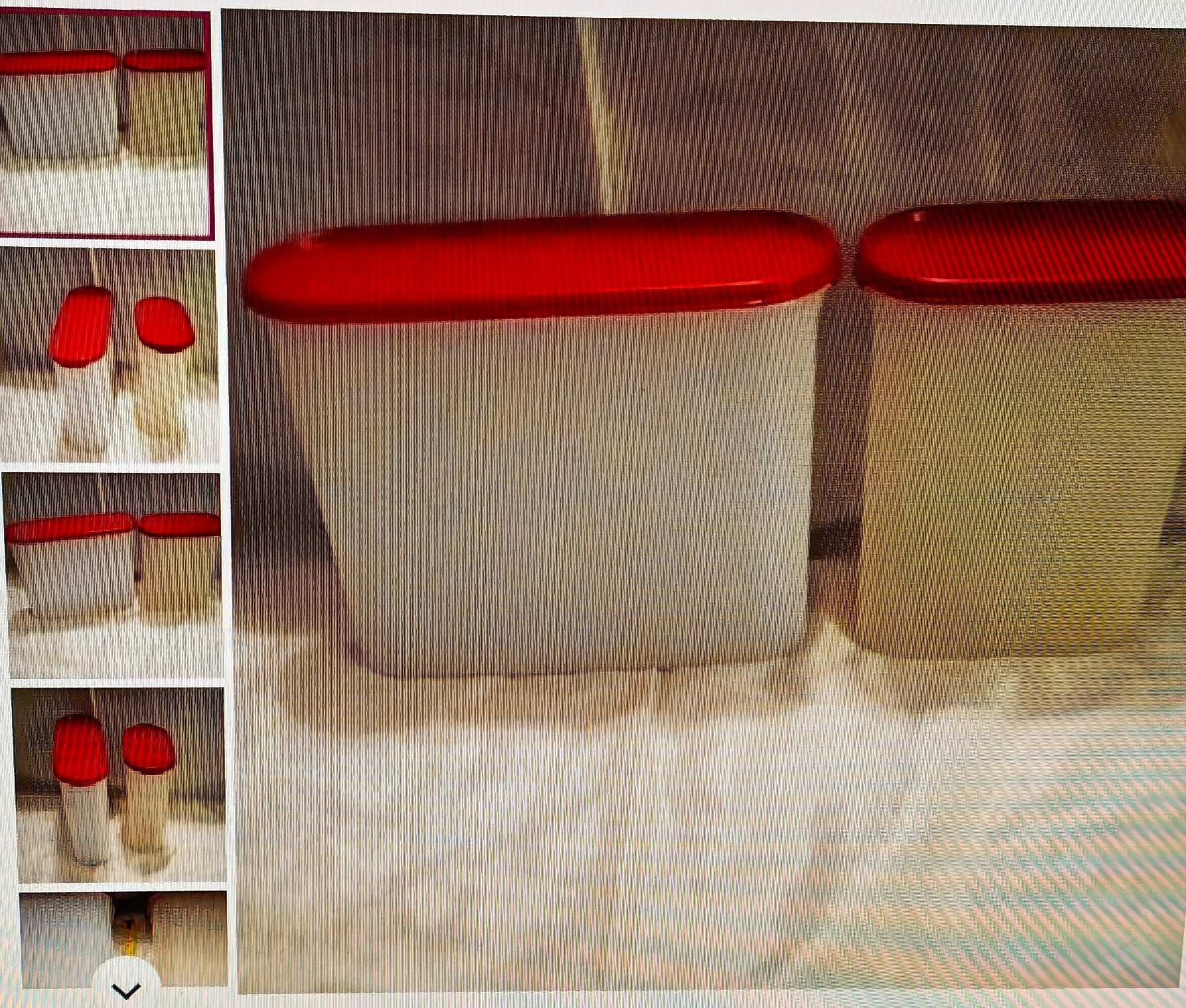 Two white storage containers with red lids on a textured surface.