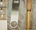 Metal bottle opener with wooden handle on a textured surface