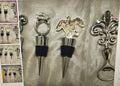 Collection of decorative bottle stoppers on a textured surface with additional stoppers in the background.
