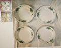 Four ceramic plates with green floral patterns on a textured surface.