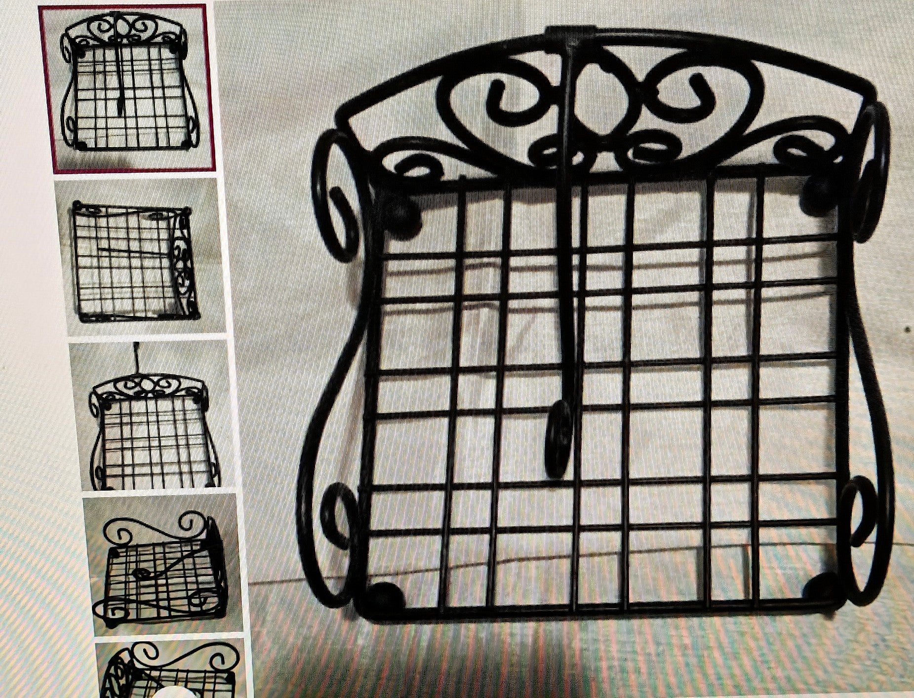 Decorative black metal grid stand with intricate designs on a textured surface.