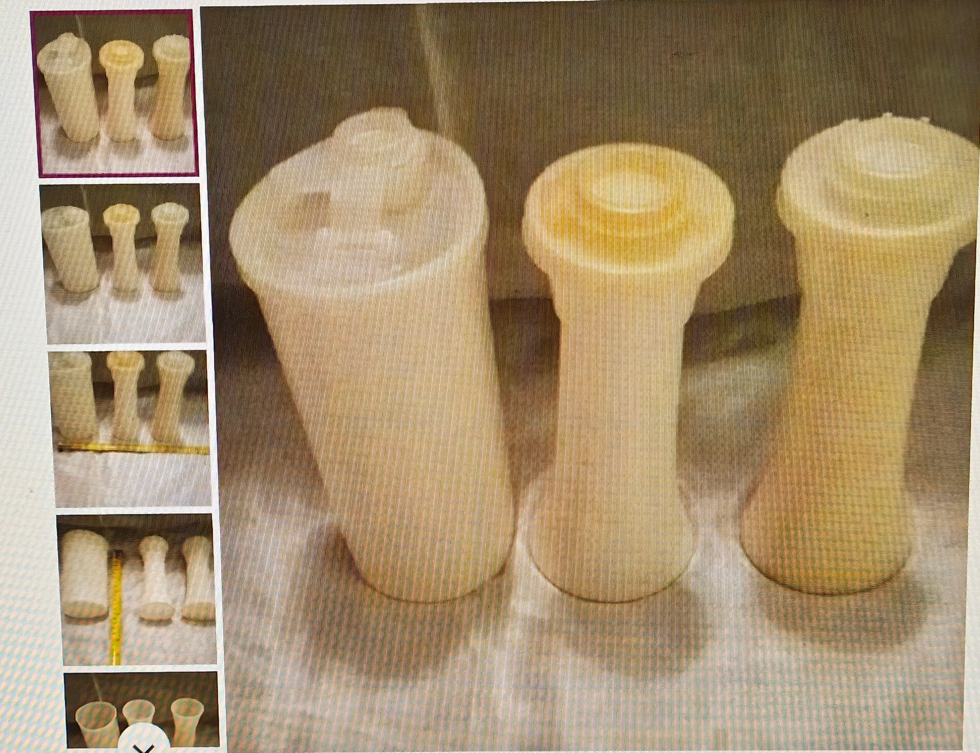 Three beige ceramic vases with textured surface on a grid background