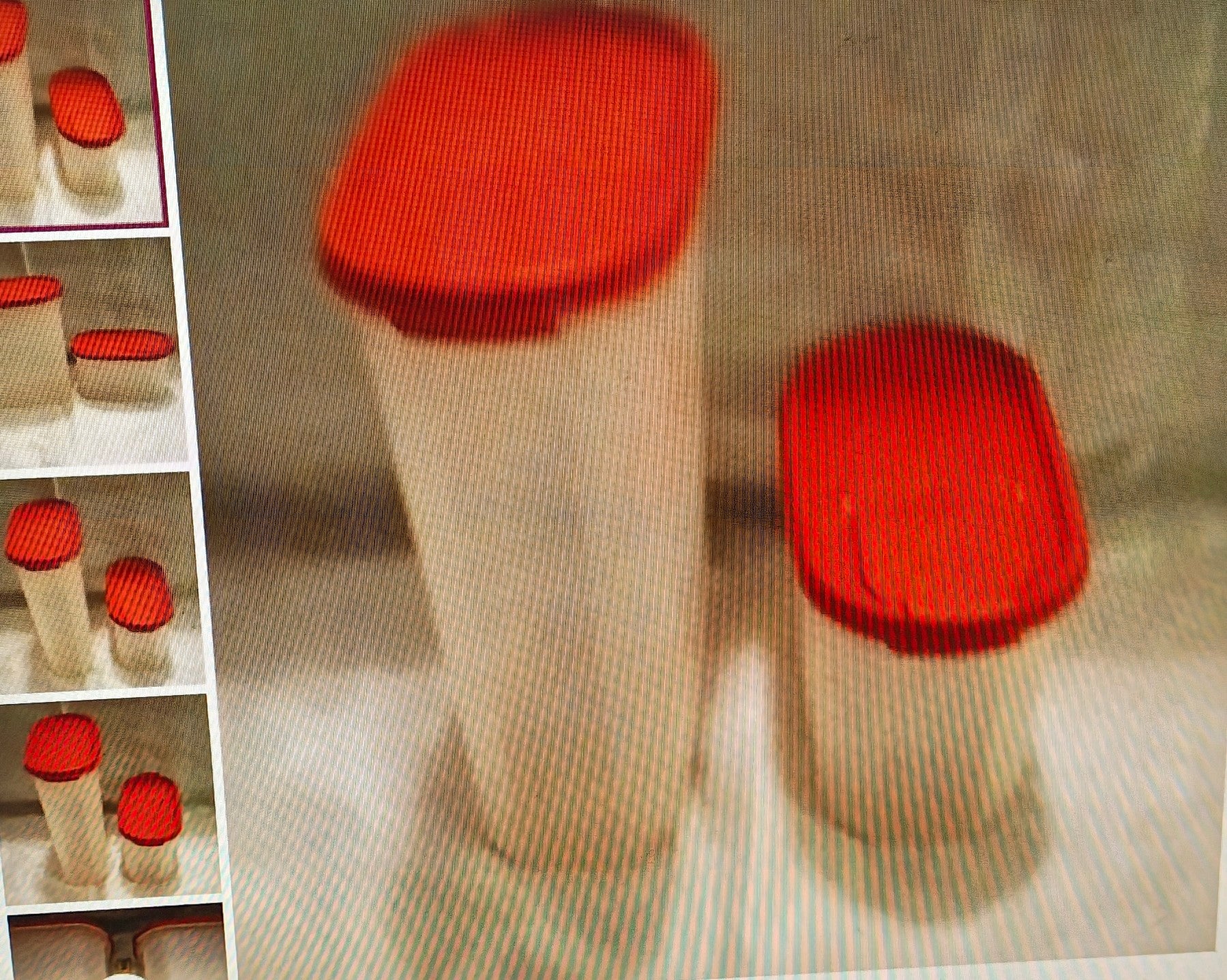 Red-lidded containers on a textured surface with a shelf in the background