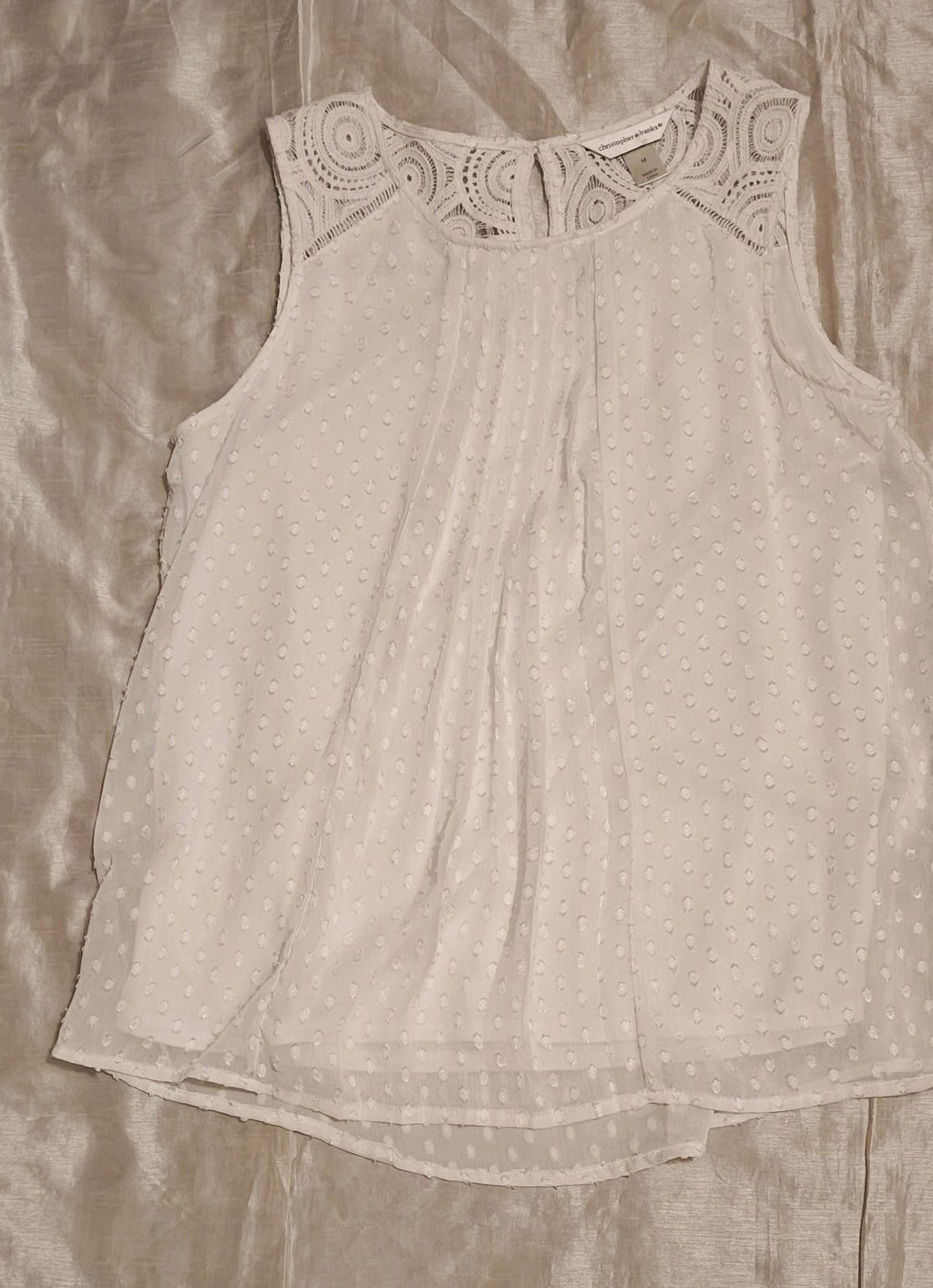 Light gray sleeveless top with lace neckline on a beige fabric background