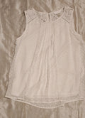 Light gray sleeveless top with lace neckline on a beige fabric background