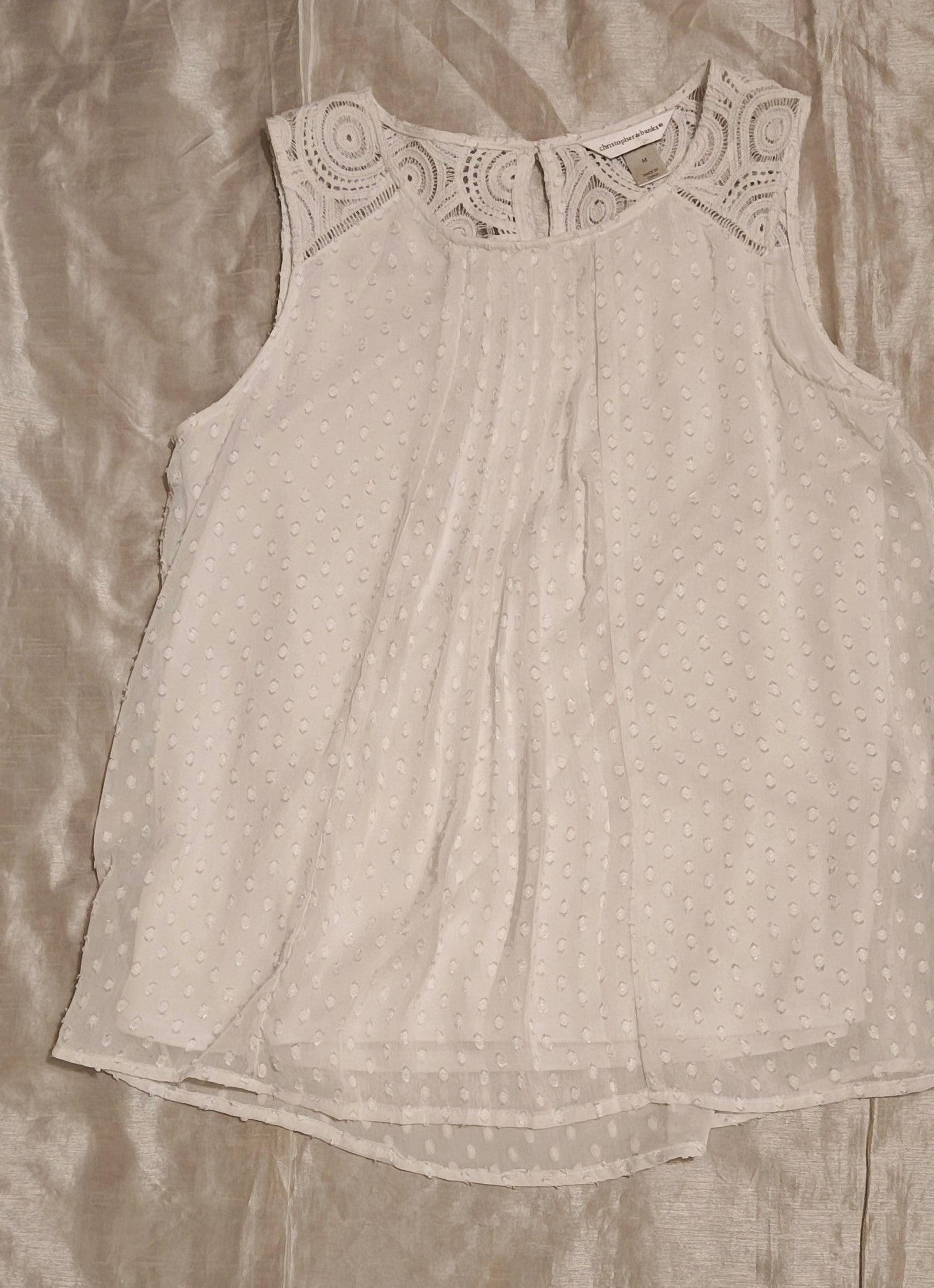 Light gray sleeveless top with lace neckline on a beige fabric background