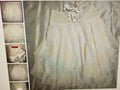 Light-colored dress with sheer overlay on a textured background