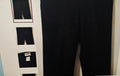 Black pants displayed on a rack with multiple pairs of pants.