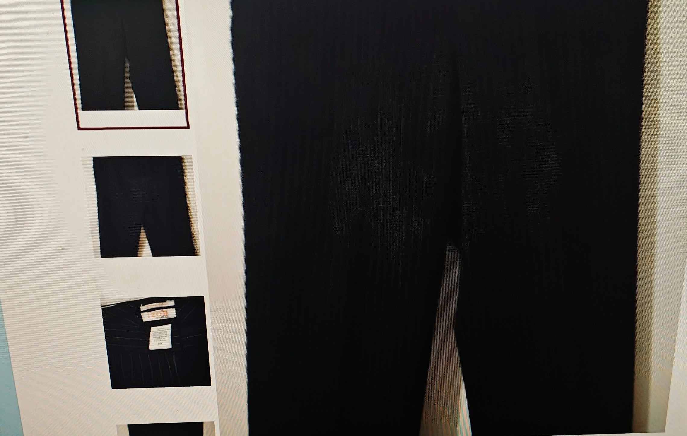 Black pants displayed on a rack with multiple pairs of pants.