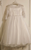 White lace dress on a hanger against a neutral background