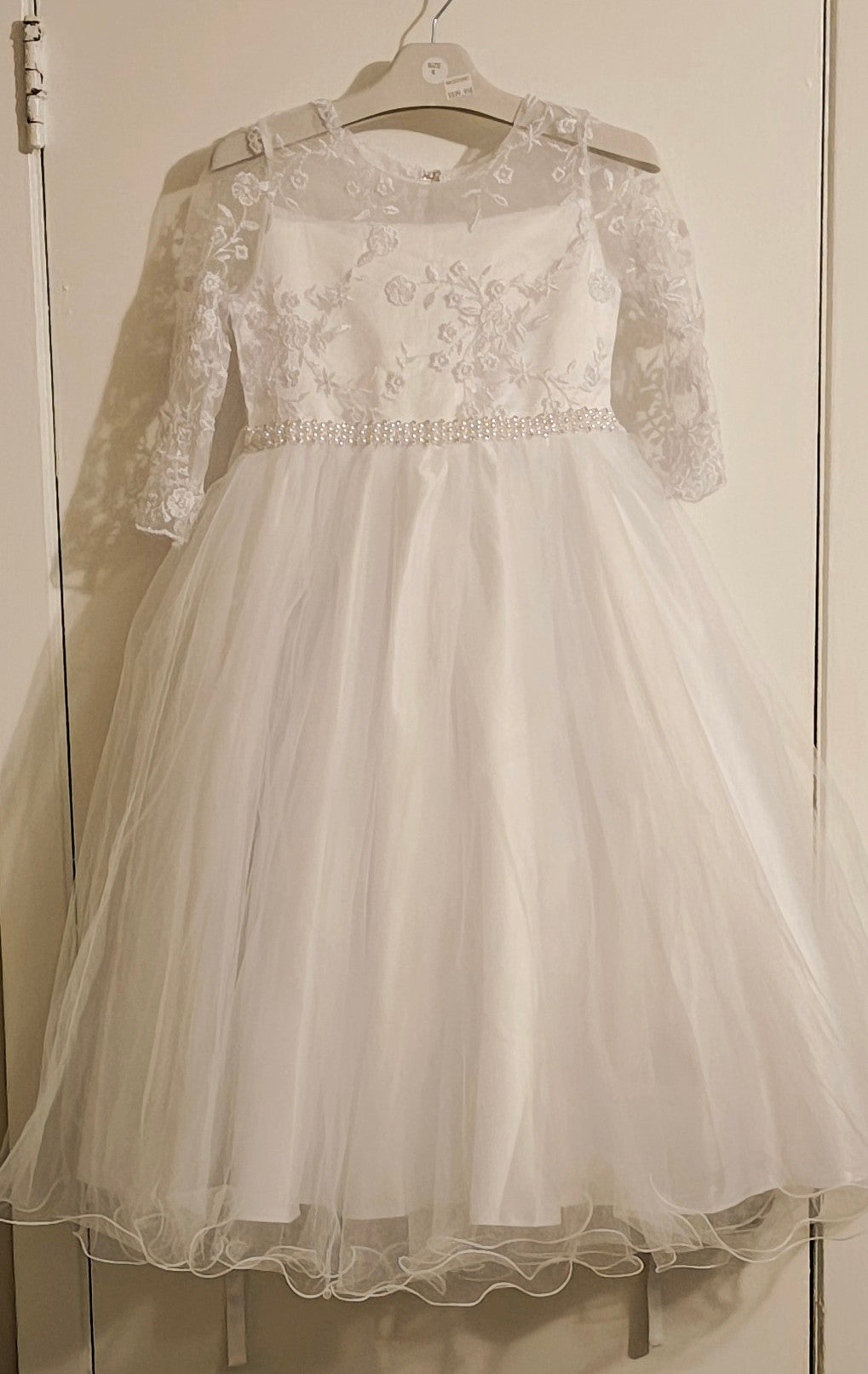 White lace dress on a hanger against a neutral background