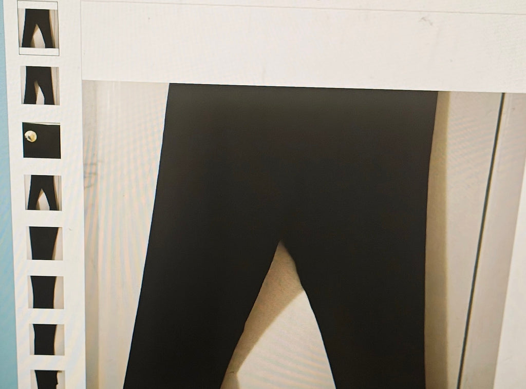 Black leggings hanging on a white rack with a neutral background