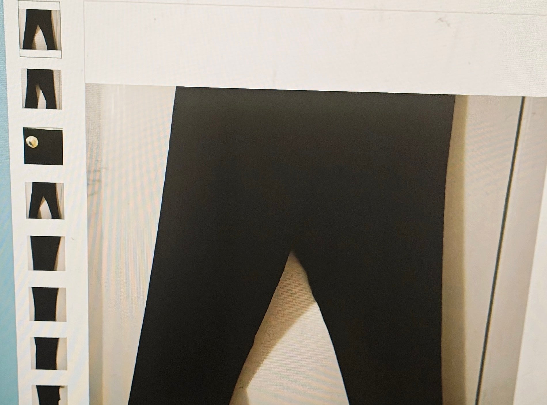 Black leggings hanging on a white rack with a neutral background