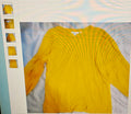 Yellow sweater displayed on a white surface with a light blue background