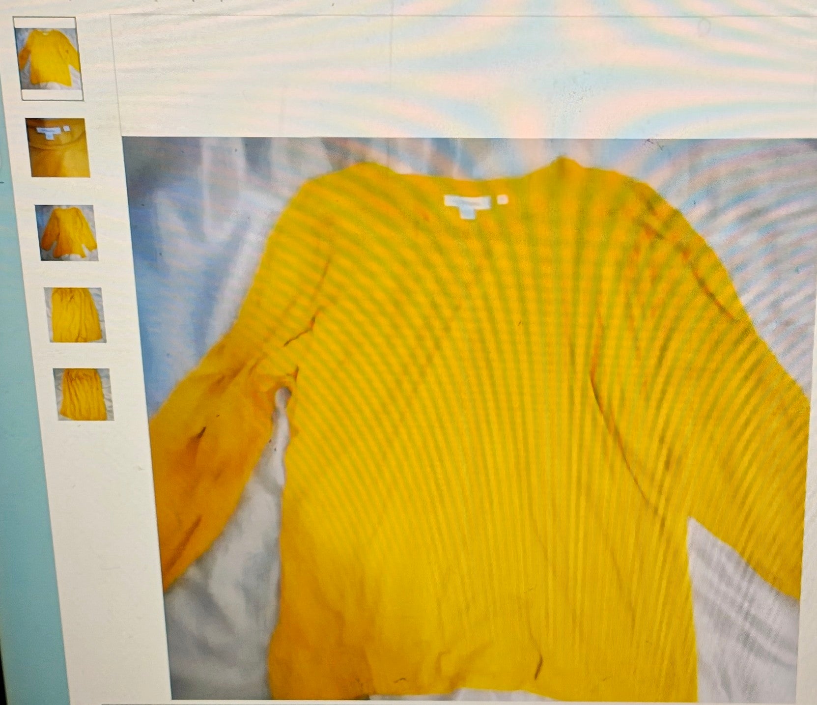 Yellow sweater displayed on a white surface with a light blue background