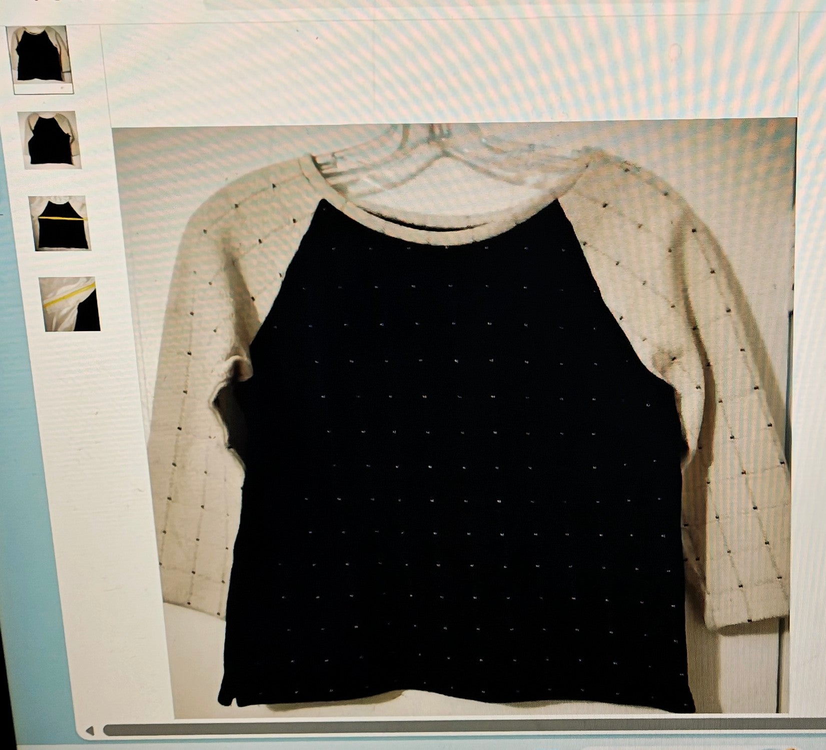 Black tank top with beige sleeves on a hanger against a light background