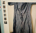 Striped suit hanging on a rack against a neutral wall.
