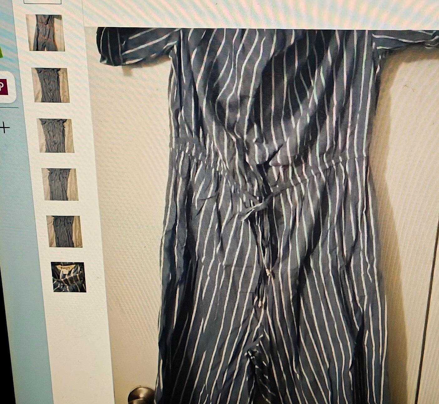Striped suit hanging on a rack against a neutral wall.