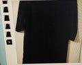 Black shirt on a hanger against a neutral background