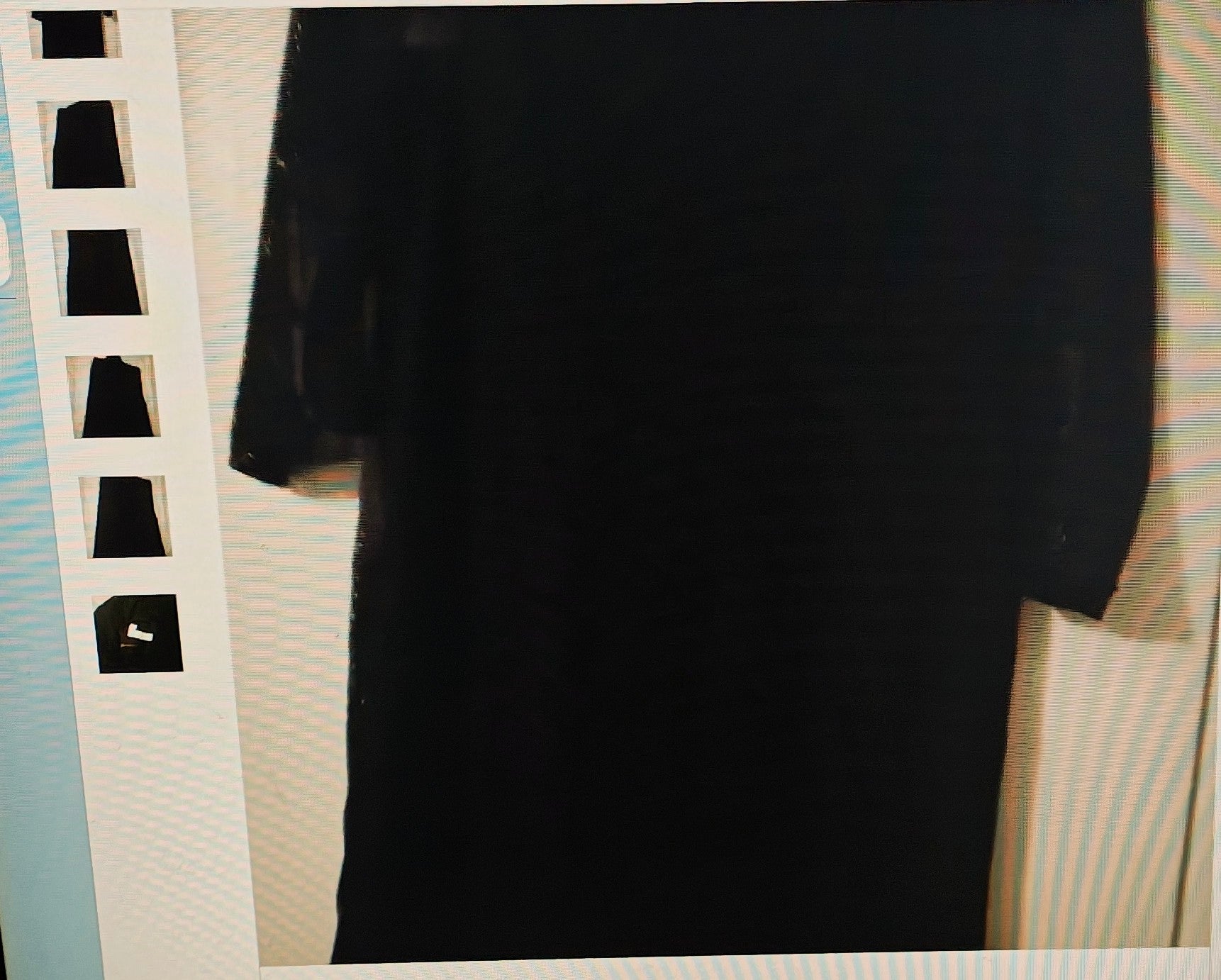 Black shirt on a hanger against a neutral background