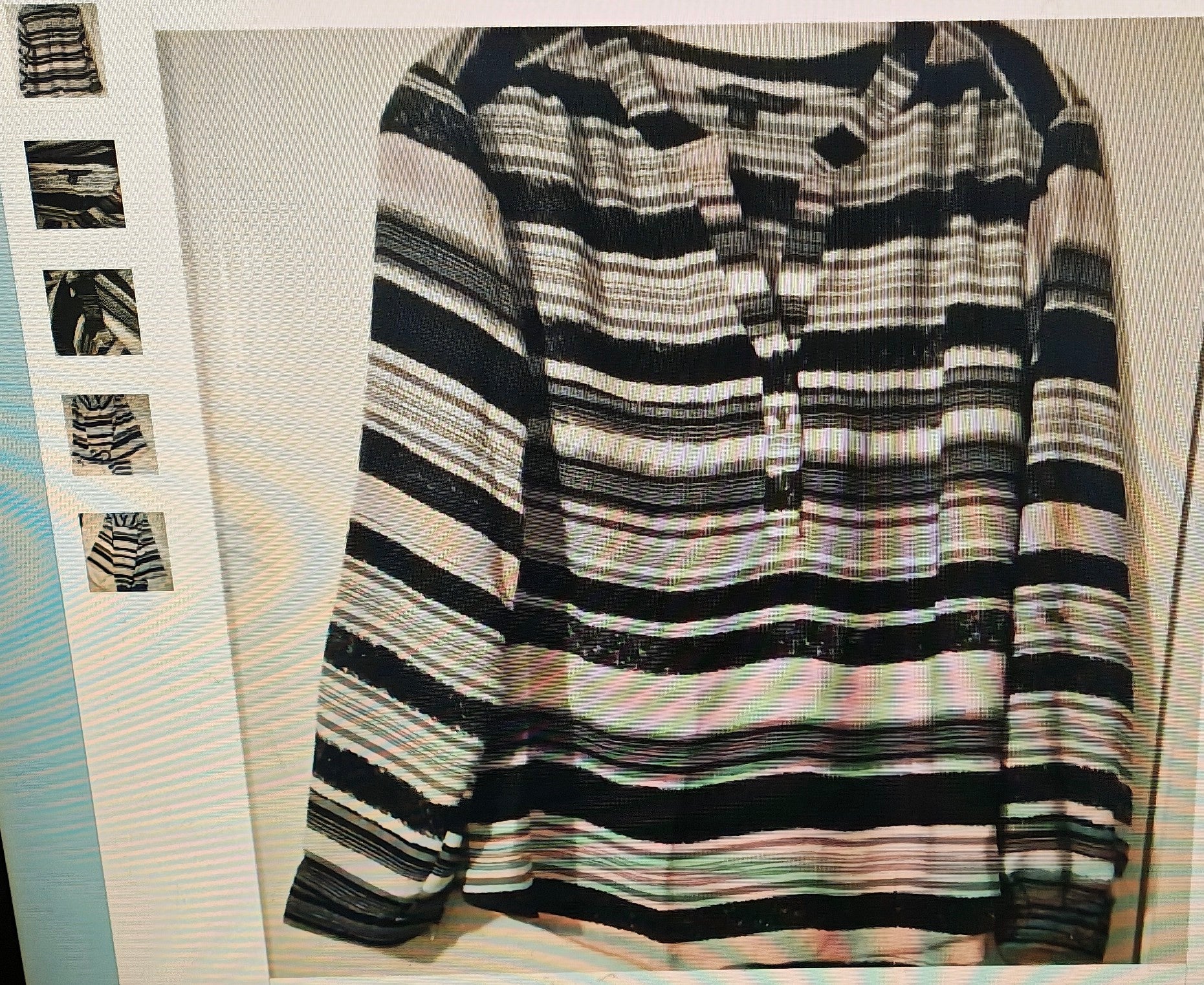 Striped sweater with black, white, and gray pattern on a flat surface.