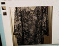 Black lace garment on a hanger against a white background