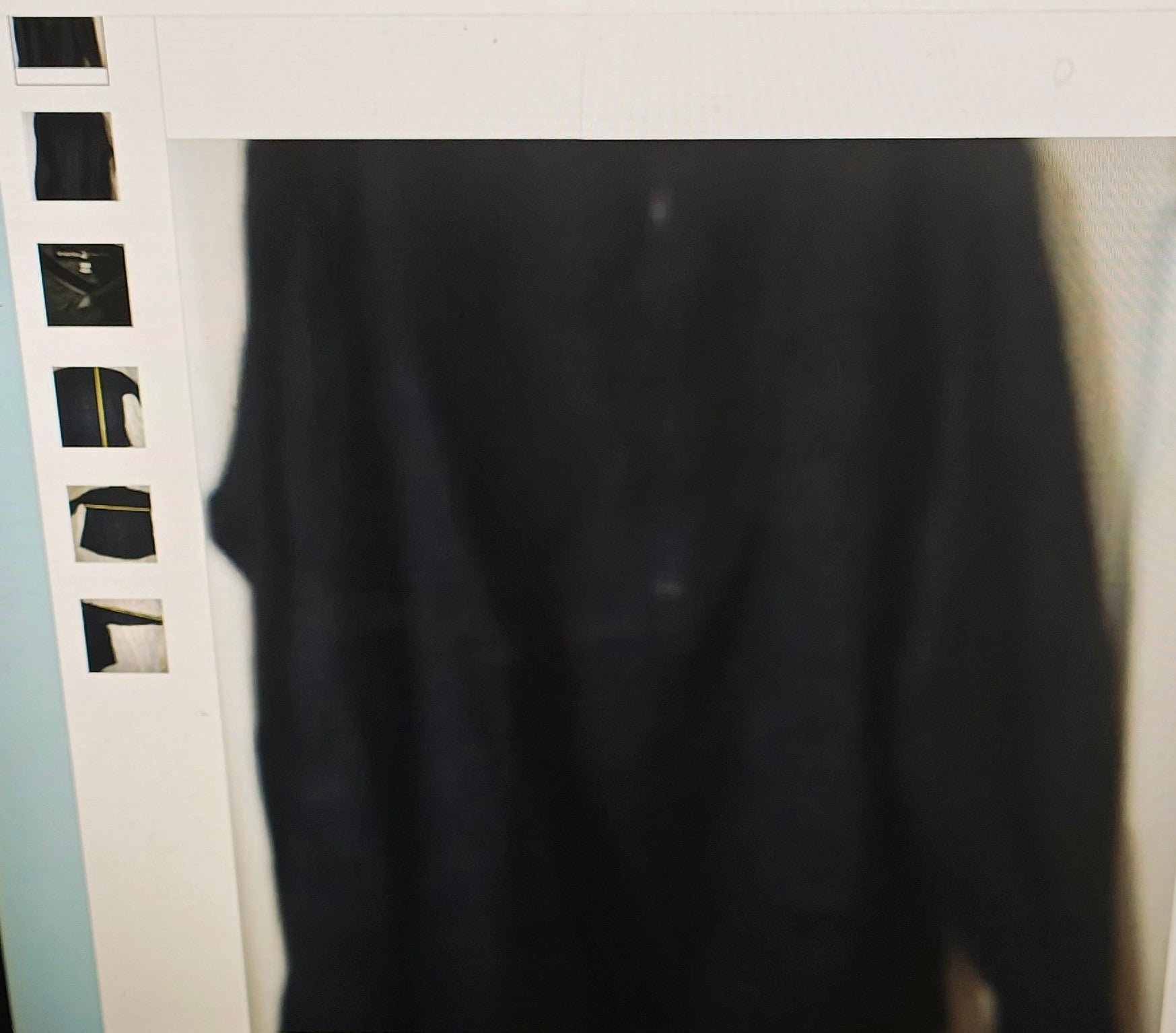 Black shirt hanging on a rack with a white background
