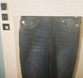 Pair of blue jeans displayed on a hanger against a neutral background